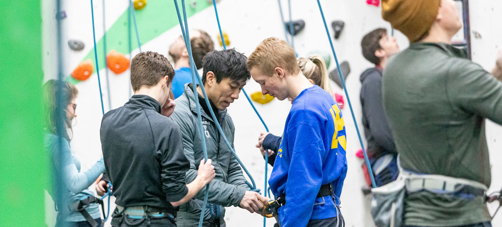 Climbing instructor showing climbers how to tie in to rope