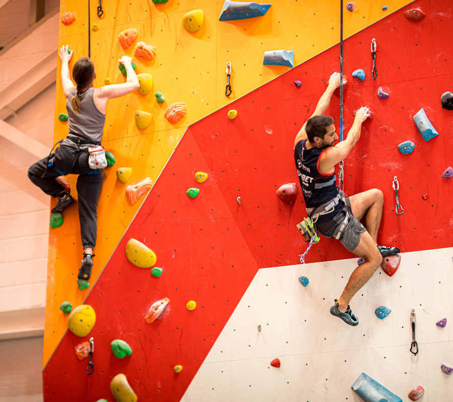 a man and woman climbing on auto belays