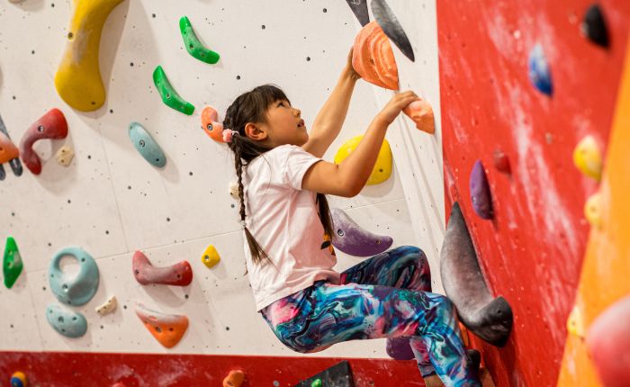 A young girl is looking up whilst bouldering