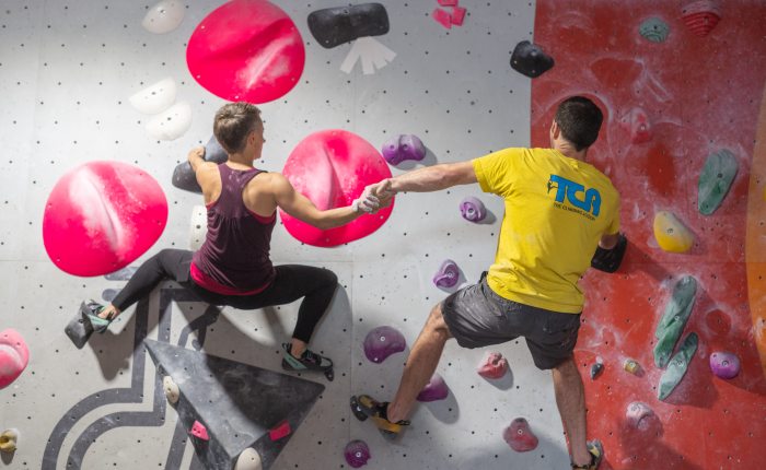 Couple holding hands climbing together on a climbing wall during an active date night in Glasgow.