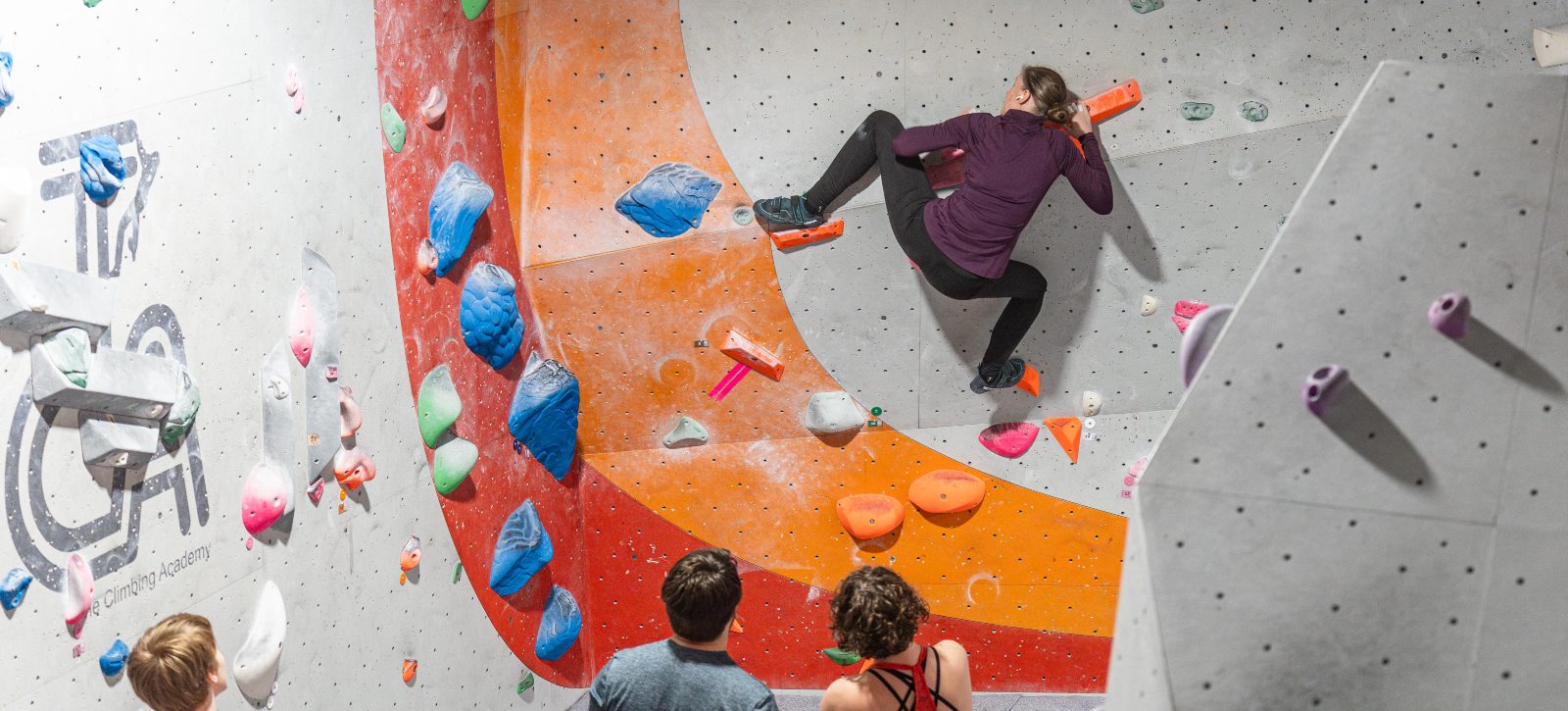 Women performing a heel hook in an indoor climbing wall
