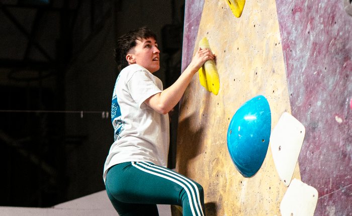 A person climbing on an indoor climbing wall at a queer climbing social