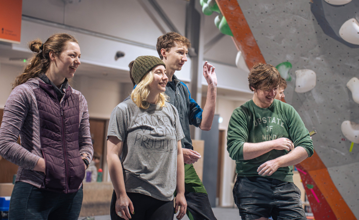 Climbers gather together looking at the climbing wall