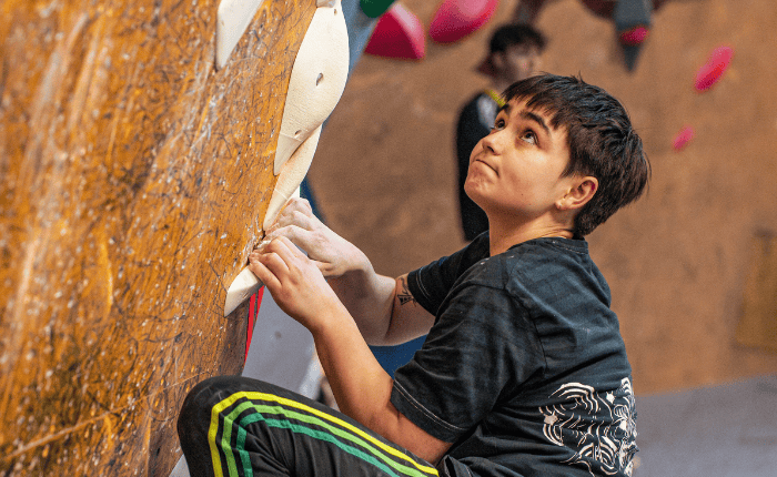 A climber looks up intensely at the next hold during a comp