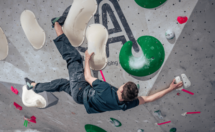 A climber stays on the wall horizontally, with a high left toe-hook above them