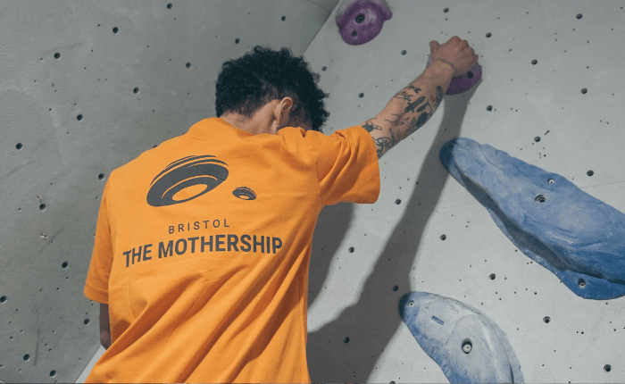 A climber (seen from behind) wearing a a Mothership tee
