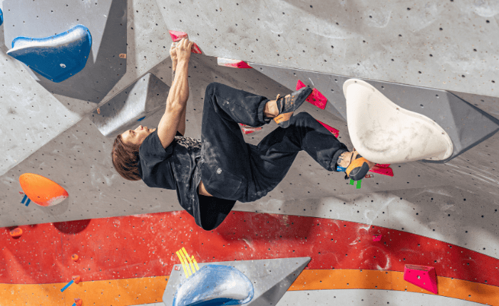 A climbers hangs horizontally on a boulder problem with a high right foot