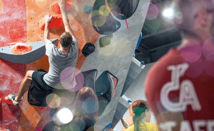Bubbles create a dreamy bokeh effect in front of a climber at The Prop Store summer comp. On the right, we see the back on a TCA staff t-shirt