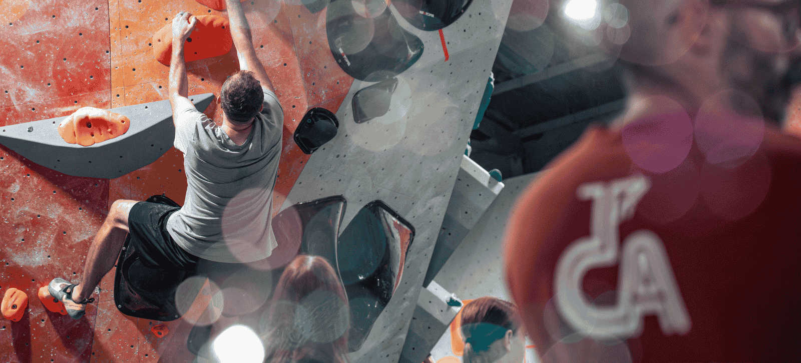 Bubbles create a dreamy bokeh effect in front of a climber at The Prop Store summer comp. On the right, we see the back on a TCA staff t-shirt