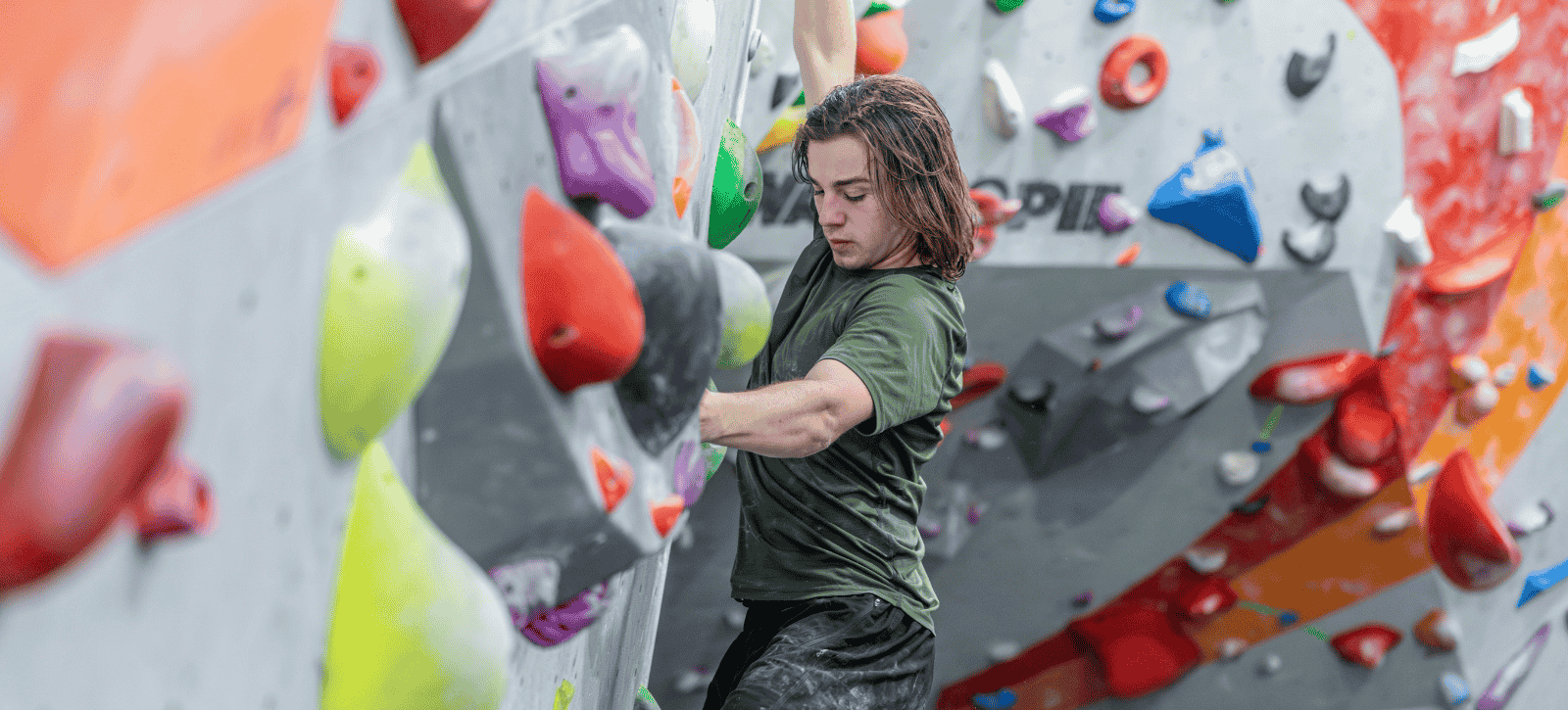 A climber looks down concentrating on his next move