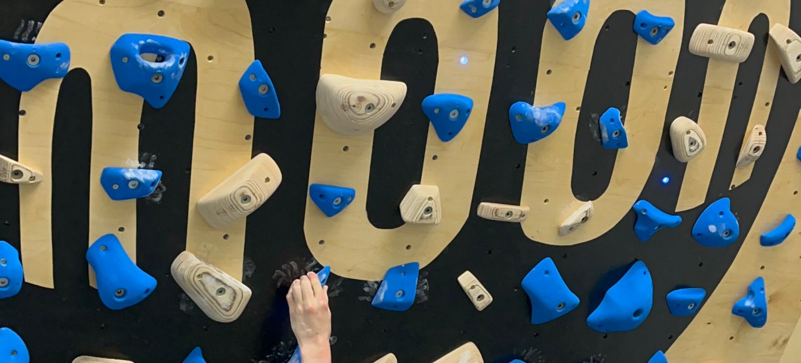Moon climbing logo on a MoonBoard with a hand holding a hold