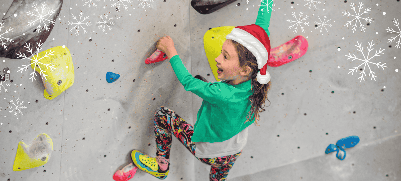 A little girls smiles as she climbs with a Christmas hat on. There are also some snowflake designs in the corners