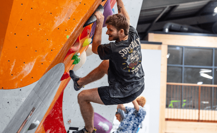 A man smiles as he smiles on a steep boulder problem