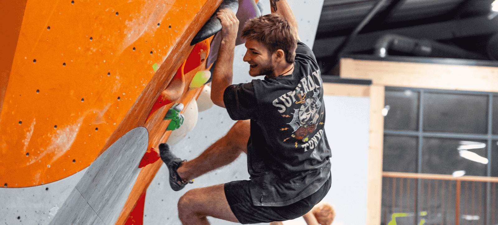 A man smiles as he smiles on a steep boulder problem