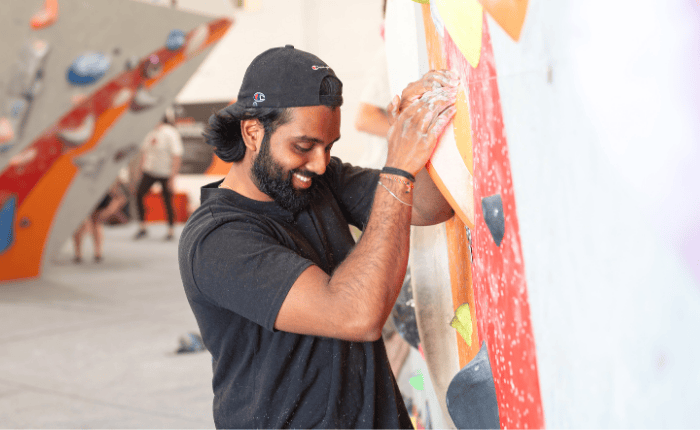 A man looks down while smiling as he starts a boulder problem