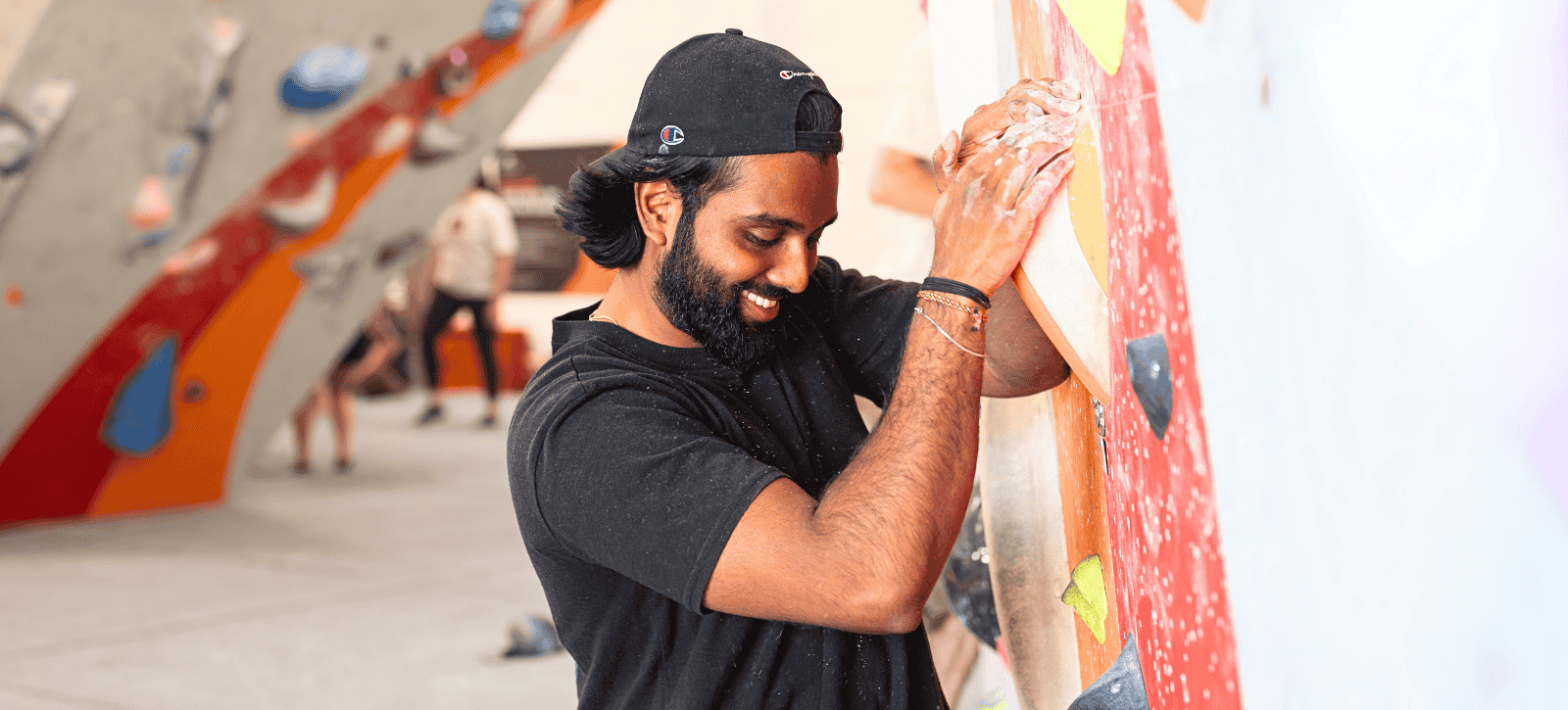 A man looks down while smiling as he starts a boulder problem