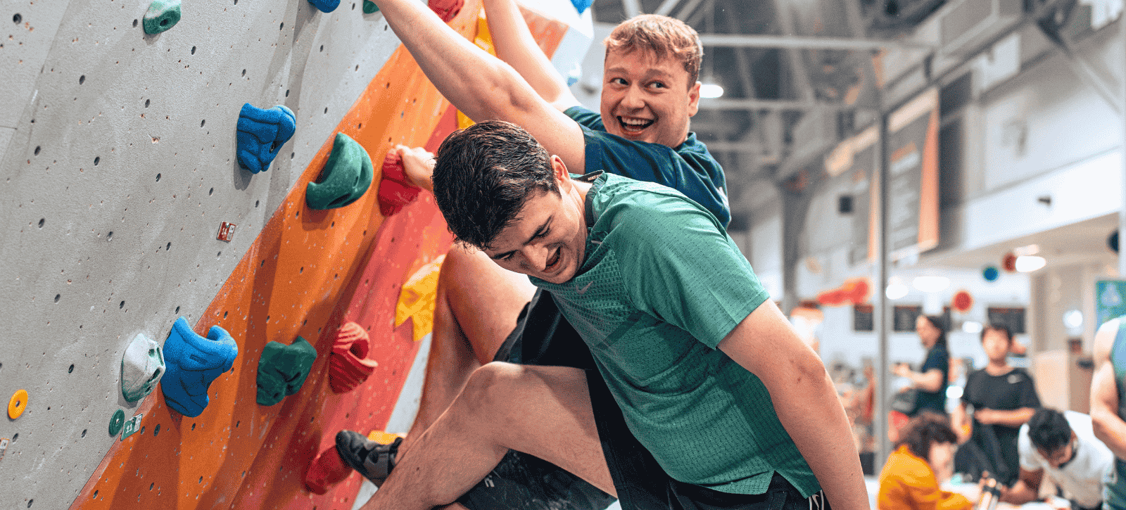 2 climbers smile as they climb on our Twister problem at a Fun Comp