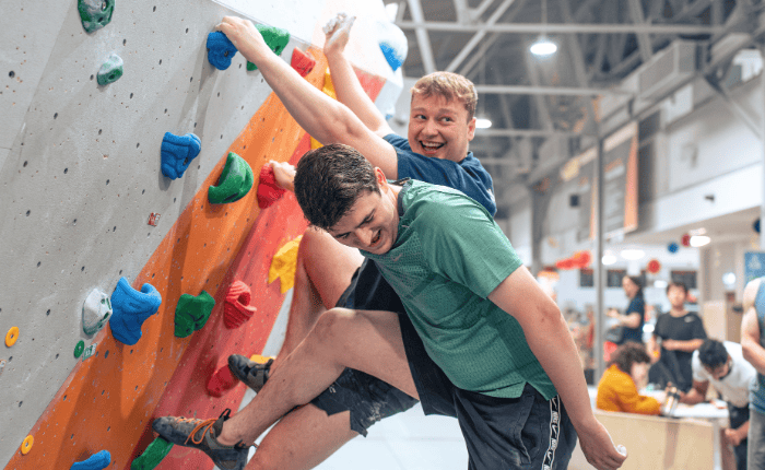 2 climbers smile as they climb on our Twister problem at a Fun Comp