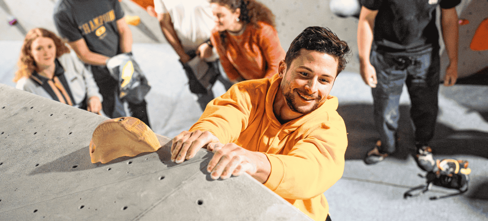 A man smiles as he reaches the top of the top-out boulder