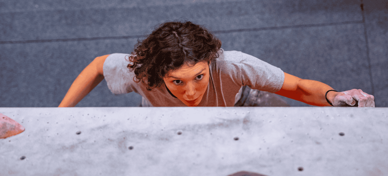 A climber is photographed from above, looking intently as their next move.