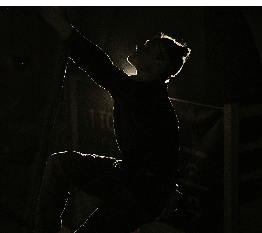We see a climber's silhouette in a black room