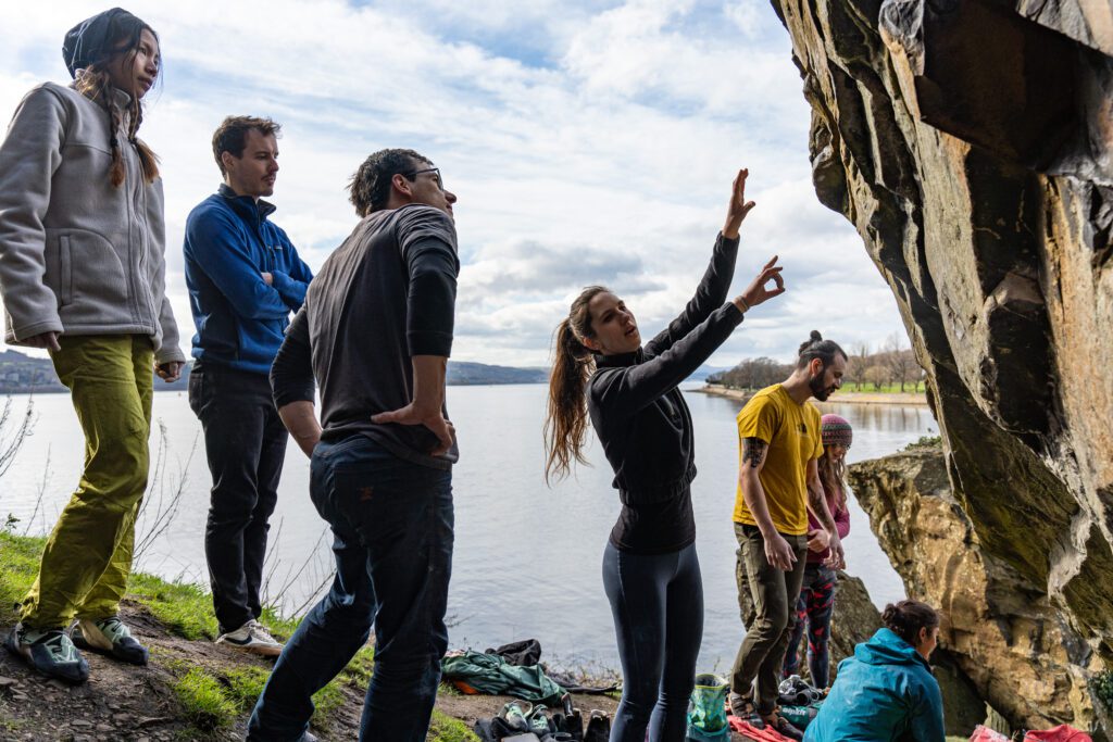 A mixed group discuss beta in front of boulders at Dumby - By Edge Photography