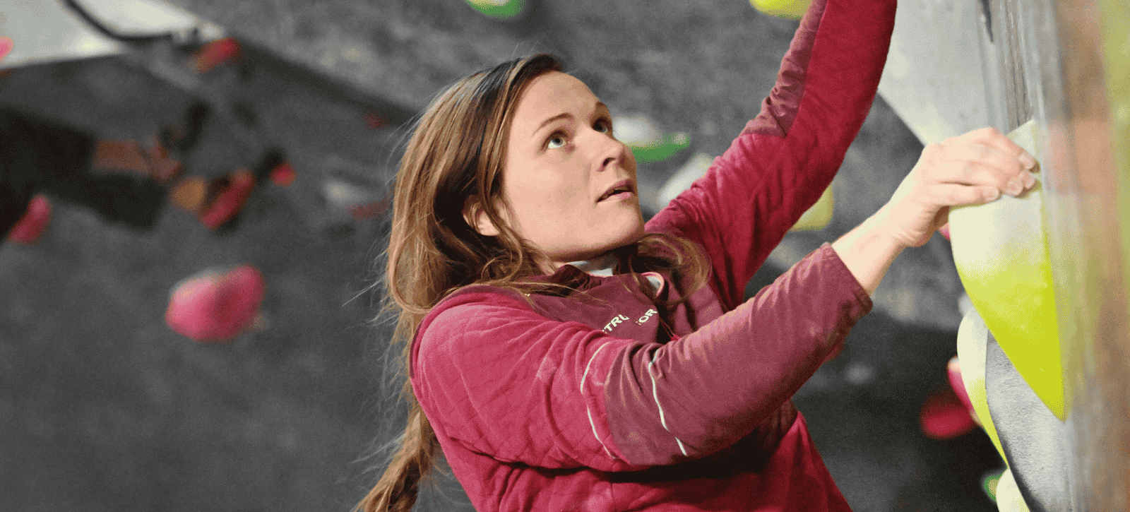 A women looks up at the next hold while bouldering