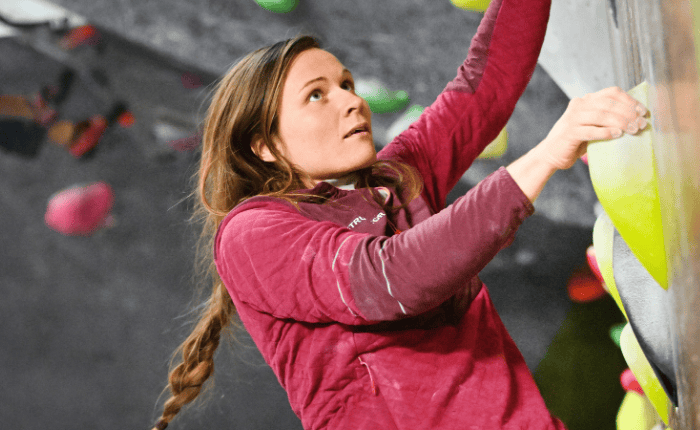 A women looks up at the next hold while bouldering