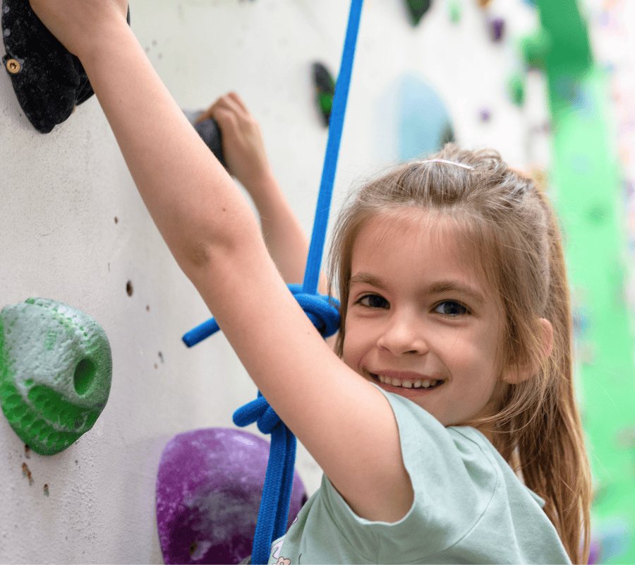 A child smiles at the camera while climbing
