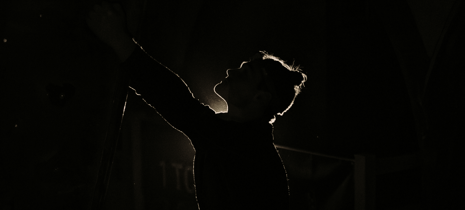 We see a climber's silhouette in a black room