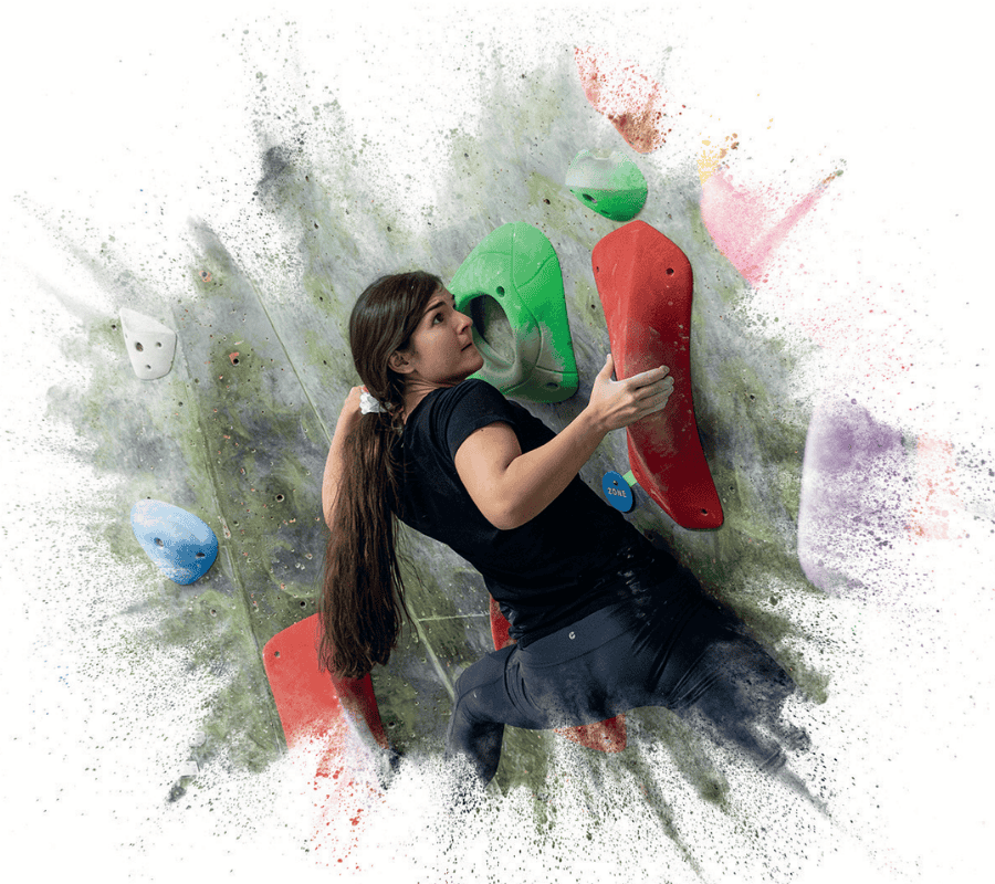 A boulderer turns her body in tight to the wall while focussing on her next move.