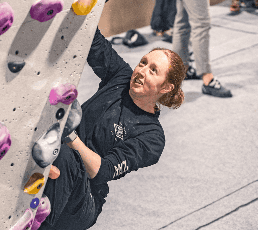 A climber looks up smiling on a boulder problem