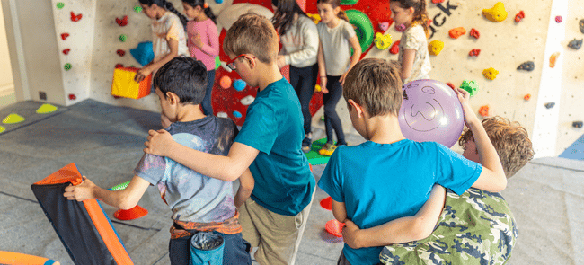 Kids clutch each other during a fun game in the kids climbing area at The Newsroom