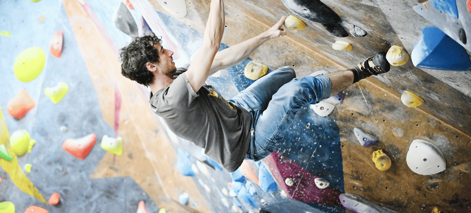 A boulderer hangs from a steep roof problem with all four limbs on holds.