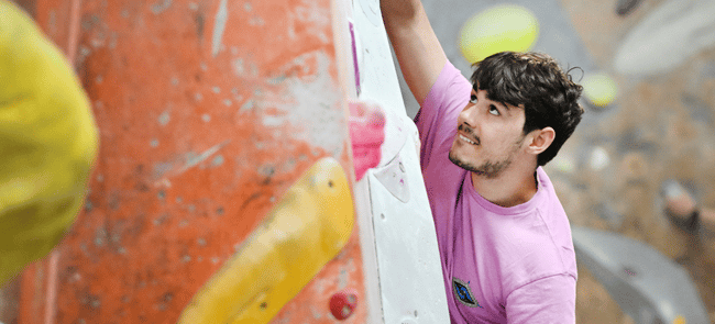 A climber smiles as he looks intently at the next hold